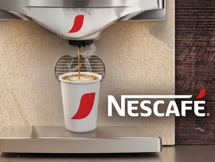Vaso de polipapel con café caliente servido en la boquilla de una máquina expendedora automática.